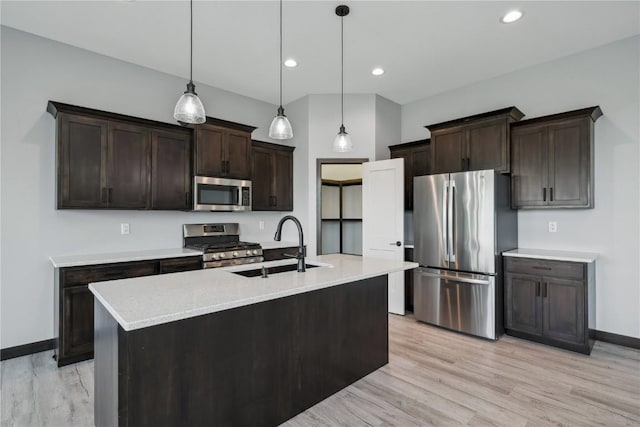 kitchen featuring light wood-type flooring, stainless steel appliances, hanging light fixtures, and sink