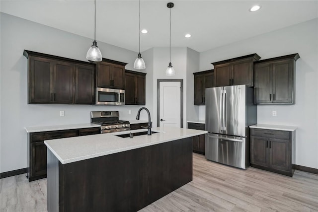 kitchen with dark brown cabinetry, sink, hanging light fixtures, stainless steel appliances, and light hardwood / wood-style flooring