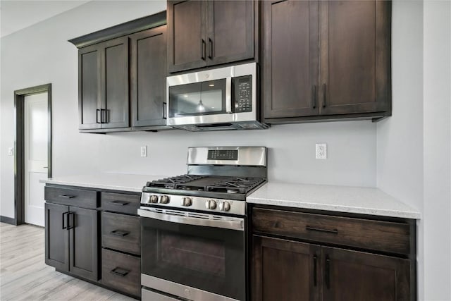 kitchen with appliances with stainless steel finishes, light wood-type flooring, and dark brown cabinets