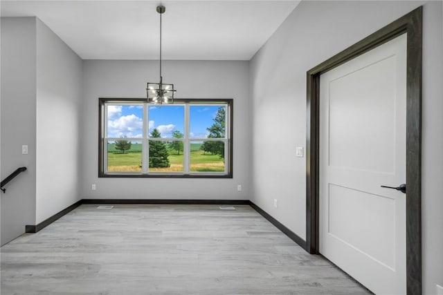 unfurnished dining area with light hardwood / wood-style floors and an inviting chandelier