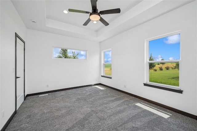 carpeted spare room featuring a raised ceiling and ceiling fan