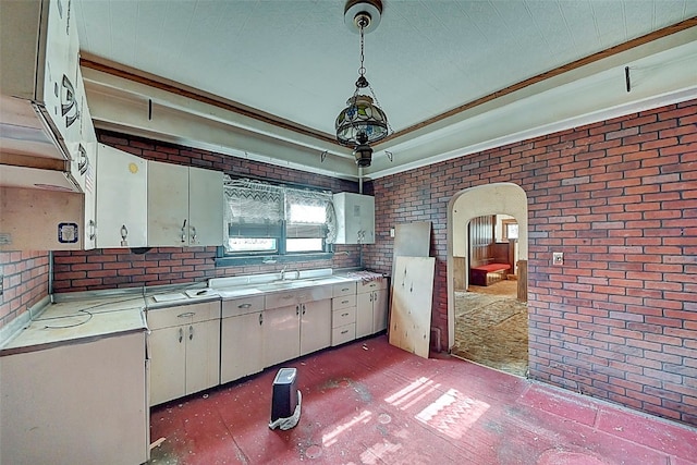 kitchen featuring pendant lighting, sink, and brick wall