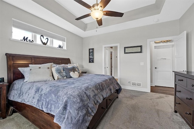 bedroom with a raised ceiling, ceiling fan, and carpet