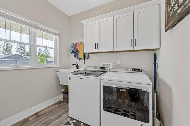 clothes washing area featuring cabinets, washing machine and dryer, light hardwood / wood-style flooring, and sink