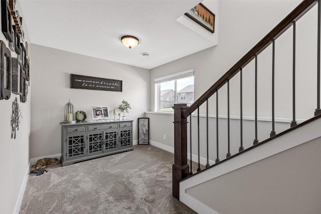 foyer featuring stairway, a textured ceiling, baseboards, and carpet