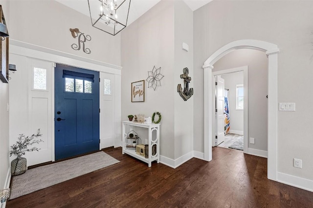 entryway with an inviting chandelier, a wealth of natural light, and dark wood-type flooring