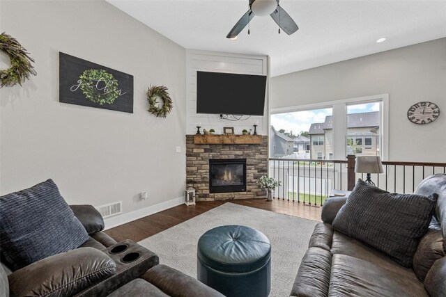 living room featuring ceiling fan, a fireplace, and dark wood-type flooring