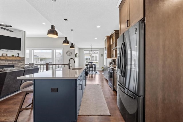 kitchen featuring a breakfast bar area, a kitchen island with sink, a sink, stainless steel appliances, and open floor plan