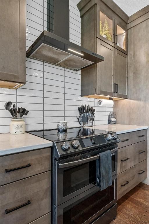 kitchen with backsplash, stainless steel range with electric stovetop, dark wood-type flooring, and wall chimney range hood