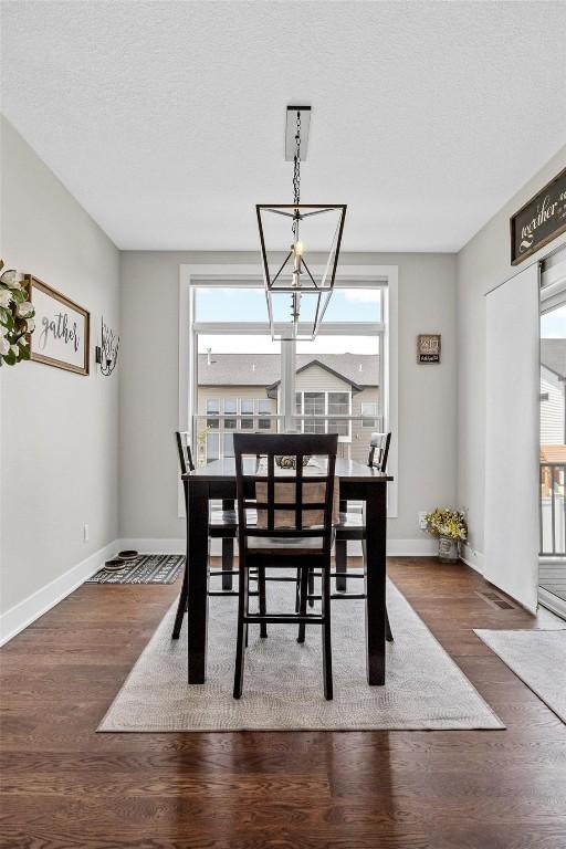 dining area featuring a textured ceiling, dark wood-type flooring, and a notable chandelier