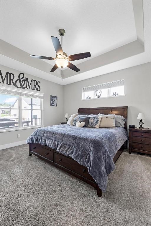 carpeted bedroom with a tray ceiling and ceiling fan