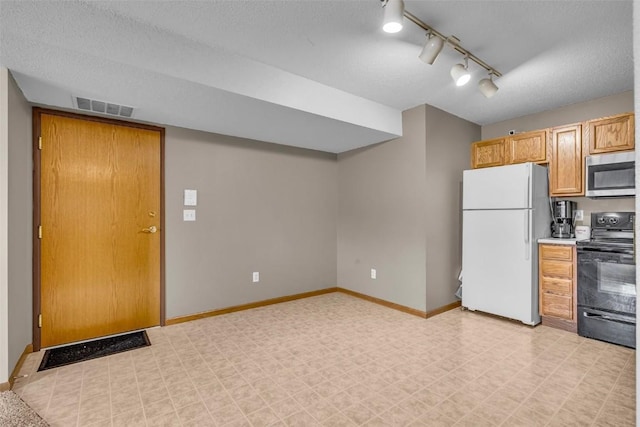 kitchen featuring a textured ceiling, white fridge, black electric range oven, and rail lighting