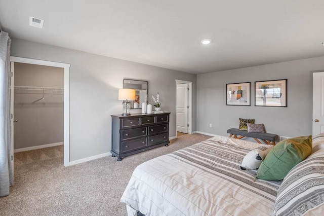 carpeted bedroom featuring a walk in closet and a closet