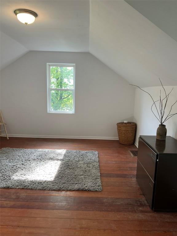 bonus room featuring lofted ceiling, dark wood-style floors, and baseboards