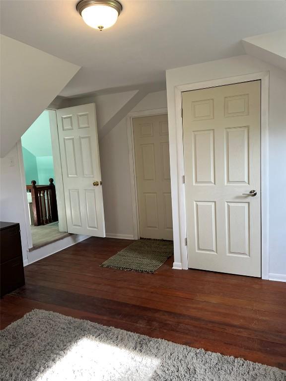 bonus room featuring dark wood-type flooring and baseboards