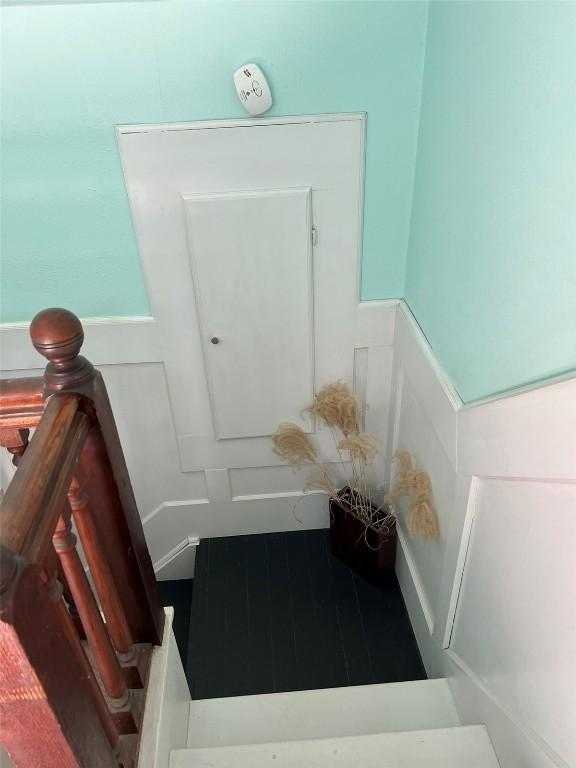 staircase featuring wainscoting and a decorative wall