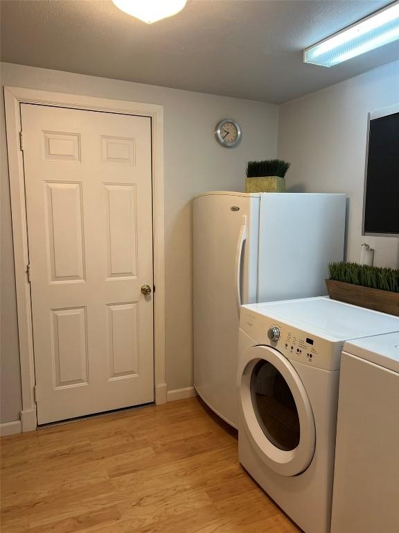 clothes washing area with light wood-type flooring, laundry area, and washer and clothes dryer