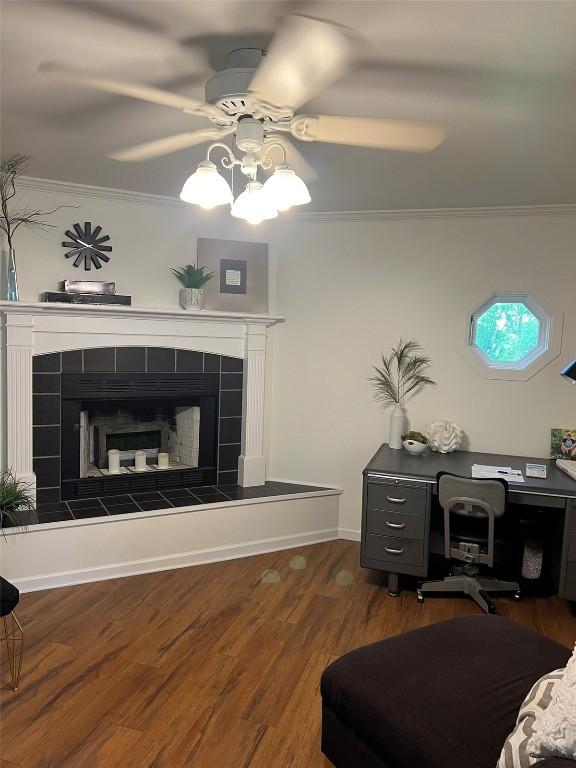 living area featuring ceiling fan, a fireplace, crown molding, and dark wood-style flooring