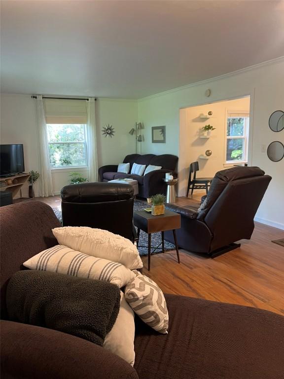 living room with crown molding and wood finished floors