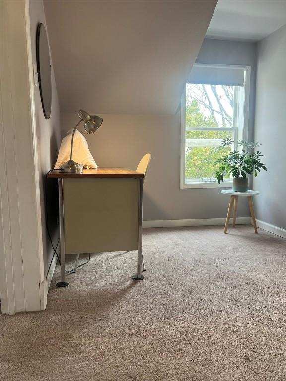 unfurnished office featuring vaulted ceiling, baseboards, and light colored carpet