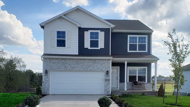 view of front of property featuring covered porch, a garage, and a front lawn