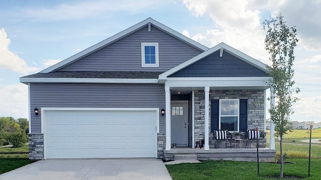 view of front of home with a front lawn, covered porch, and a garage