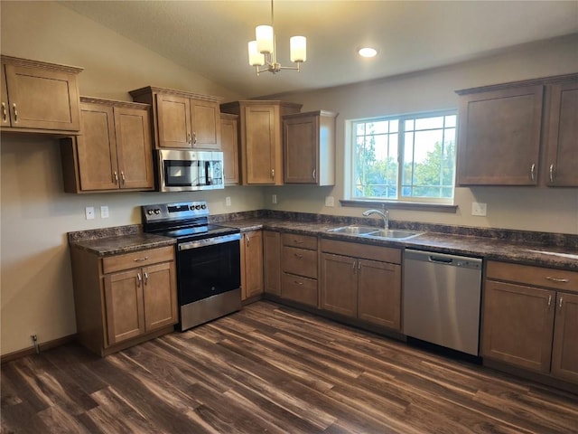 kitchen with appliances with stainless steel finishes, dark countertops, a sink, and lofted ceiling