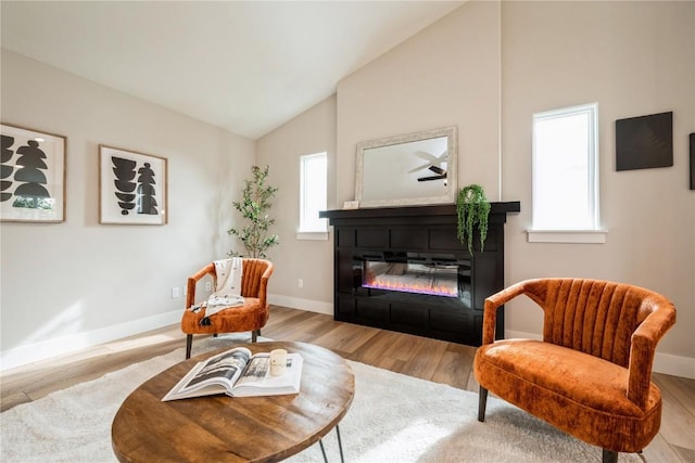 sitting room featuring lofted ceiling, baseboards, and wood finished floors