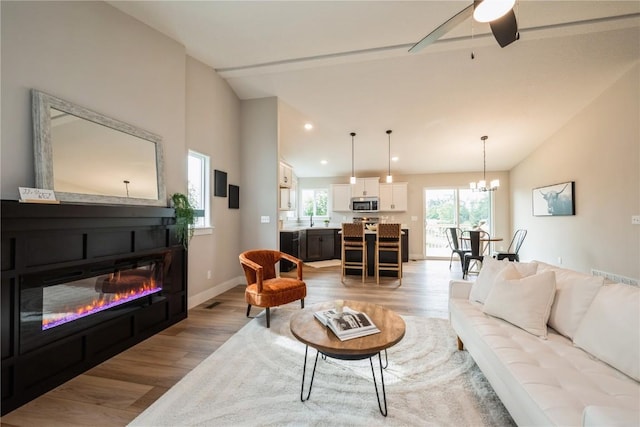 living area with lofted ceiling, light wood-type flooring, baseboards, and recessed lighting