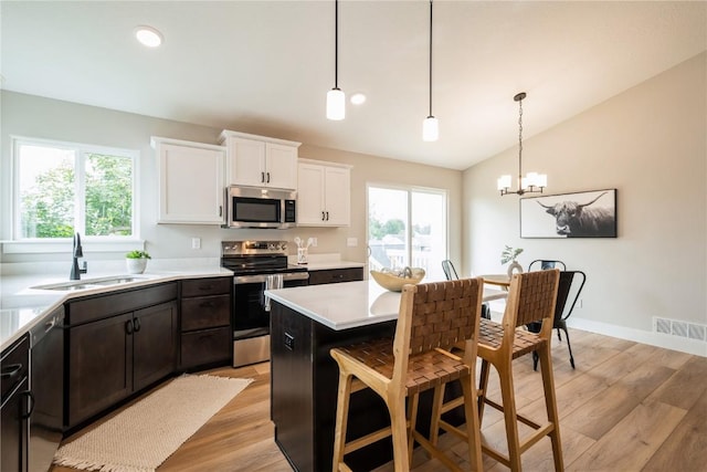 kitchen with lofted ceiling, a sink, visible vents, white cabinetry, and appliances with stainless steel finishes