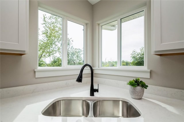 details featuring light stone counters, white cabinets, and a sink