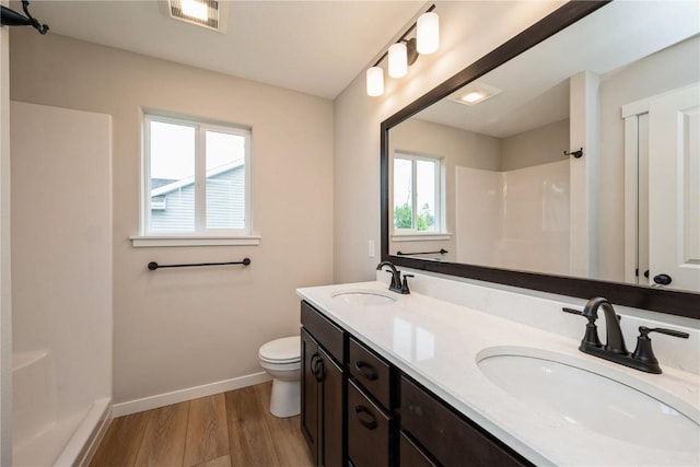 bathroom featuring visible vents, a sink, baseboards, and walk in shower