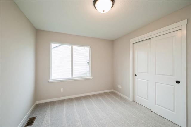 unfurnished bedroom featuring a closet, carpet, visible vents, and baseboards