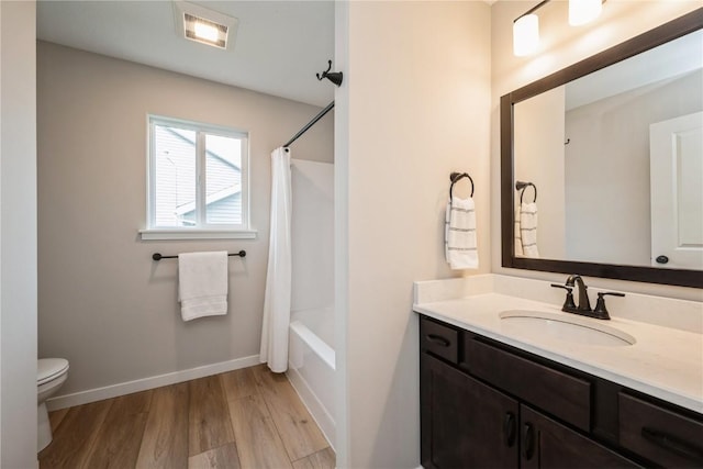 full bath featuring baseboards, toilet, wood finished floors, shower / bathtub combination with curtain, and vanity