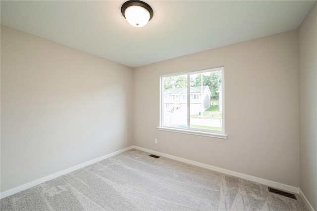 spare room with carpet, visible vents, and baseboards