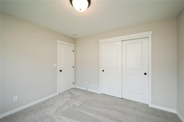 unfurnished bedroom featuring baseboards, visible vents, a textured ceiling, carpet floors, and a closet