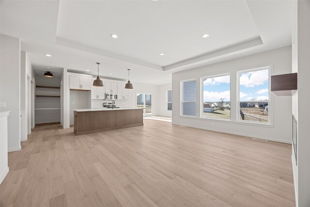 unfurnished living room featuring light hardwood / wood-style floors and a tray ceiling