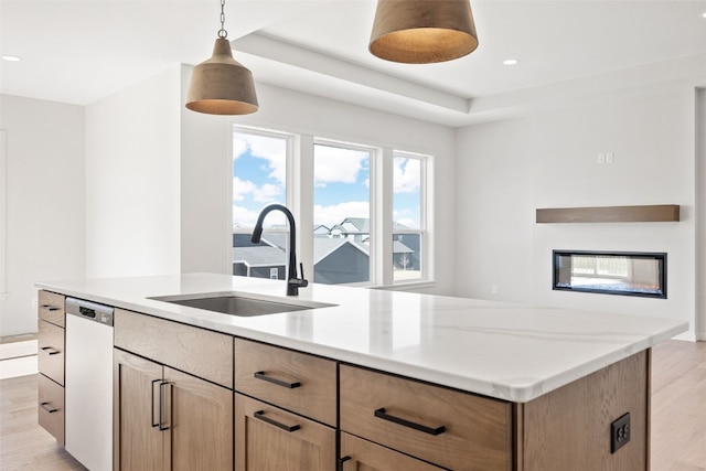 kitchen with sink, hanging light fixtures, dishwasher, and light wood-type flooring