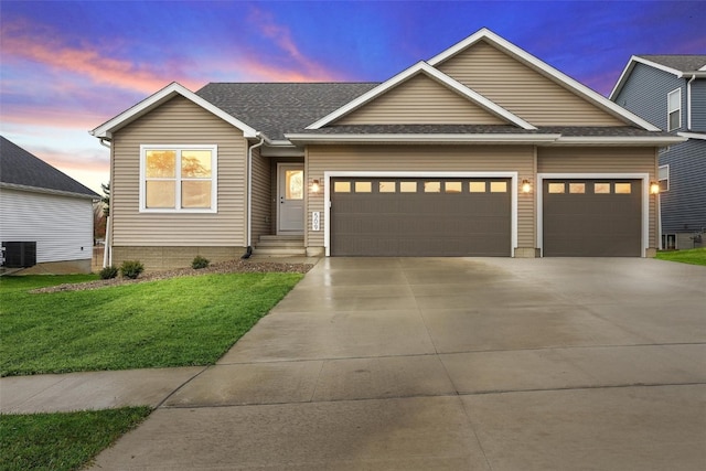 view of front of property featuring cooling unit, a yard, and a garage