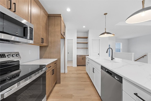 kitchen featuring sink, light stone counters, light hardwood / wood-style flooring, white cabinets, and appliances with stainless steel finishes