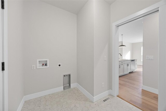 washroom with hookup for an electric dryer, hookup for a washing machine, light wood-type flooring, and sink