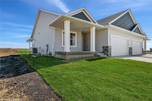 view of front of home with a front yard, central AC unit, covered porch, and a garage