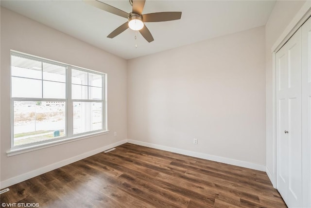 empty room featuring dark wood-type flooring and ceiling fan