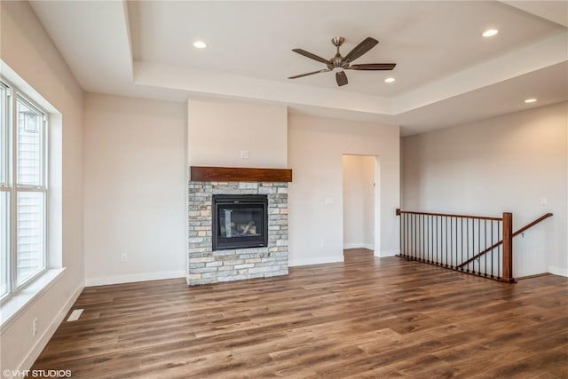 unfurnished living room with ceiling fan, dark hardwood / wood-style floors, a fireplace, and a tray ceiling