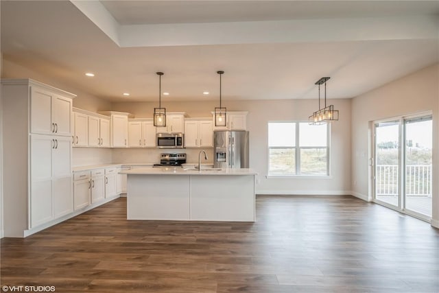 kitchen featuring pendant lighting, sink, appliances with stainless steel finishes, white cabinetry, and a center island with sink