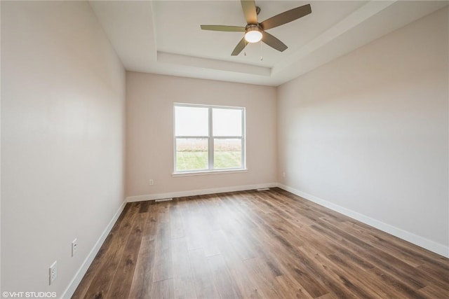 spare room with a tray ceiling, wood-type flooring, and ceiling fan