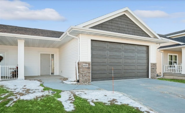 snow covered garage featuring a porch