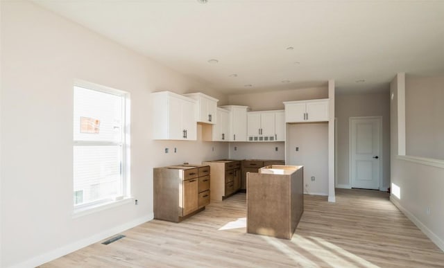 kitchen featuring a center island, white cabinets, and light wood-type flooring