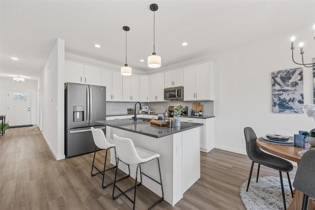 kitchen with white cabinetry, hardwood / wood-style flooring, stainless steel appliances, and an island with sink