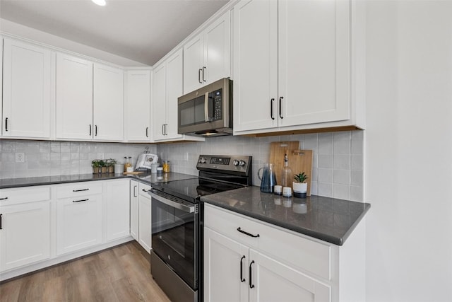 kitchen with appliances with stainless steel finishes, light hardwood / wood-style flooring, white cabinets, and tasteful backsplash